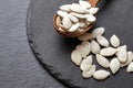 Pumpkin seeds and a wooden spoon on a dark table. Black slateboard with wooden bowl. Copy space Royalty Free Stock Photo