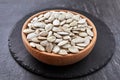 Pumpkin seeds and a wooden spoon on a dark table. Black slateboard with wooden bowl. Copy space Royalty Free Stock Photo