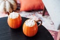 Pumpkin shaped cups of hot drink with marshmallows on black wooden table in cozy interior. Pumpkin latte. Cozy autumn