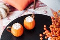Pumpkin shaped cups of hot drink with marshmallows on black wooden table in cozy interior. Pumpkin spice latte. Cozy