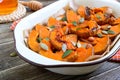 Pumpkin slices baked in the oven with honey, nuts, cinnamon, seeds, mint. Pieces of pumpkin lying on the baking paper in a bowl.