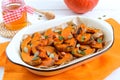 Pumpkin slices baked in the oven with honey, nuts, cinnamon, seeds, mint. Pieces of pumpkin lying on the baking paper in a bowl.