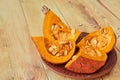 Pumpkin slices with seeds on the brown plate on the wooden background. Ingredients for tasty diet autumn dish