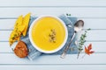 Pumpkin soup decorated seeds and thyme in white bowl on blue table top view. Flat lay styling. Royalty Free Stock Photo