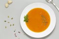 Pumpkin soup with herbs, cream and pumpkin seeds served in white bowl. Seasonal autumn food - Spicy pumpkin soup.