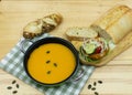 Pumpkin soup next to a patty on bread with tomatoes, onions and lettuce Royalty Free Stock Photo