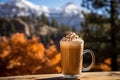 Pumpkin Spice Latte in tall glass on wooden table outdoors with autumn mountainous view on the background Royalty Free Stock Photo