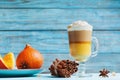 Pumpkin spiced latte or coffee in glass on turquoise rustic table. Autumn, fall or winter hot drink.