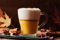 Pumpkin spiced latte or coffee in a glass on a wooden vintage table. Autumn or winter hot drink