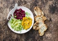 Pumpkin, turmeric, avocado, beetroot hummus with olive oil, sesame seeds and microgreens on a wooden background, top view. Delicio Royalty Free Stock Photo