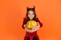 Pumpkin vegetable in hands of happy devil kid wear horns costume of imp on halloween party, selective focus, halloween Royalty Free Stock Photo