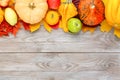 Pumpkins with colorful maple leaves, ripe apples, ashberry and pear on wooden background. Autumn thanksgiving seasonal image with