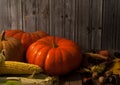 Pumpkins, corn, apples, walnuts and chestnuts, autumn leaves on a wooden background. Royalty Free Stock Photo