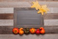 Autumn leaves, pumpkins on wooden background with copy space on chalkboard Royalty Free Stock Photo