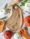Pumpkins frame of various sizes and colors and different raw herbs and a spices and wood board on a marble background. Top view.