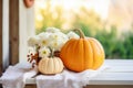 Pumpkins near white flowers on a wood table. Farmhouse autumn centerpiece on blurred backyard background. Cottagecore aesthetic Royalty Free Stock Photo