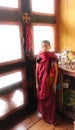 Punakha, Bhutan - September 10, 2016: Young novice Buddhist monk in reddish robe standing in front of a window inside a monastery. Royalty Free Stock Photo