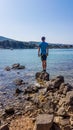 Punat - Young man standning on a rocks in a shallow sea water Royalty Free Stock Photo