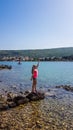 Punat - Young woman stadnig on the rocks in a shallow sea water Royalty Free Stock Photo