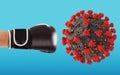 Punch with boxing glove hits the virus on cyan background Royalty Free Stock Photo