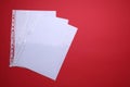 Punched pockets with paper sheets on red background, flat lay. Space for text