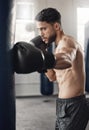 Punching bag, boxing and boxer man in workout training or exercise in a gym. Strong, powerful and serious athlete or