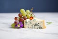 pungent blue cheese wedge on marble with grapes