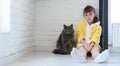 The punished girl sits in the corner of the room, a large domestic cat sits nearby