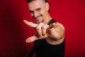 Punk with black electric guitar, mustache and big mohawk showing horn gesture. Photo of a rock musician in the studio on a red Royalty Free Stock Photo