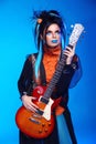 Punk rock girl guitarist posing over blue studio background. Trendy model with hairstyle. Model isolated on blue studio background Royalty Free Stock Photo