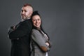 punk-style man and woman dressed in jacket suits pose smiling in studio shot