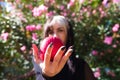 Punky girl with blonde and brunette hair holds a red apple in her hands and stares at it. The girl is a witch from the fairy tale Royalty Free Stock Photo