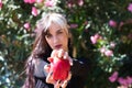 Punky girl with blonde and brunette hair holds a red apple in her hands and stares at it. The girl is a witch from the fairy tale Royalty Free Stock Photo