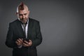 punky-style man dressed in jacket suit looks at his phone in studio shot Royalty Free Stock Photo
