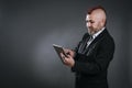 punky-style man looks at his tablet dressed in business suit in camera shot Royalty Free Stock Photo
