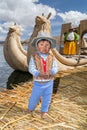 Puno, Peru - circa June 2015: Small boy in traditional clothes and canoe boat at Uros floating island and village on Lake Titicaca