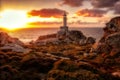 Punta Nariga Lighthouse surrounded by the sea and rocks during the sunset in Spain Royalty Free Stock Photo