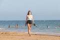 Punta Umbria, Huelva, Spain - August 7, 2020: A young Woman listening music is walking by the beach wearing protective or medical