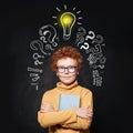 Pupil boy looking at camera on chalkboard background with lightbulb Royalty Free Stock Photo