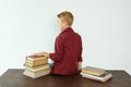 Pupil boy sits at the table with his back to the camera, next to the books