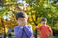 Pupil bullying another in the yard at the elementary school. Older boy offends younger kid. Laughing on his back. Small child Royalty Free Stock Photo