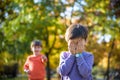 Pupil bullying another in the yard at the elementary school. Older boy offends younger kid. Laughing on his back. Small child Royalty Free Stock Photo