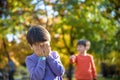 Pupil bullying another in the yard at the elementary school. Older boy offends younger kid. Laughing on his back. Small child Royalty Free Stock Photo