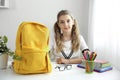 Pupil child sitting at the desk with books and backpack. School supplies.Back to school concept. School girl prepare staff for Royalty Free Stock Photo
