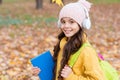 Pupil in earpieces hold book while walking in park, education Royalty Free Stock Photo