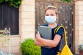 Pupil with face mask holding book outdoor. Back to school Royalty Free Stock Photo