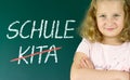 Pupil in front of a blackboard with the German words: Schule statt Kita (school instead of daycare) Royalty Free Stock Photo