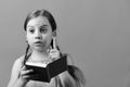 Pupil in pink dress with braids. Girl holds open notebook Royalty Free Stock Photo