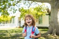 Pupil of primary school with book in hand near school park. Schoolboy with backpack near building outdoors. Beginning of Royalty Free Stock Photo