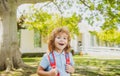 Pupil of primary school with book in hand near school park. Schoolboy with backpack near building outdoors. Beginning of